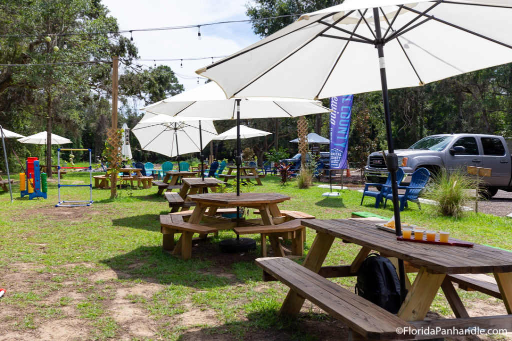 picnic tables with white umbrellas on top of grassy area