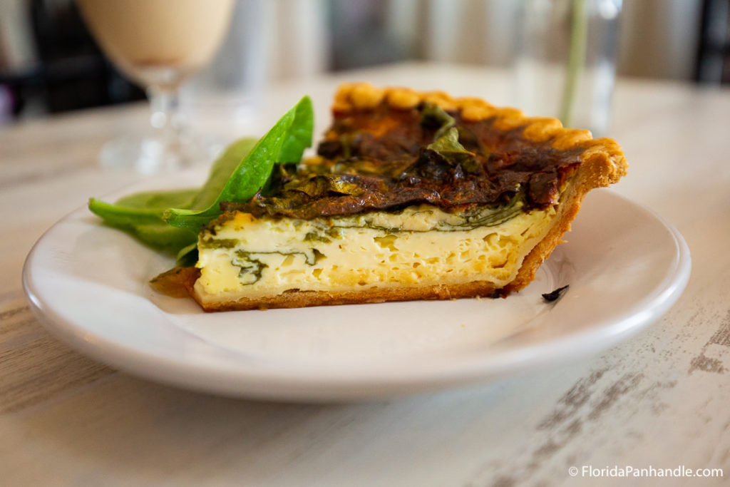 a spinach and egg quiche with spinach leaves on the side
