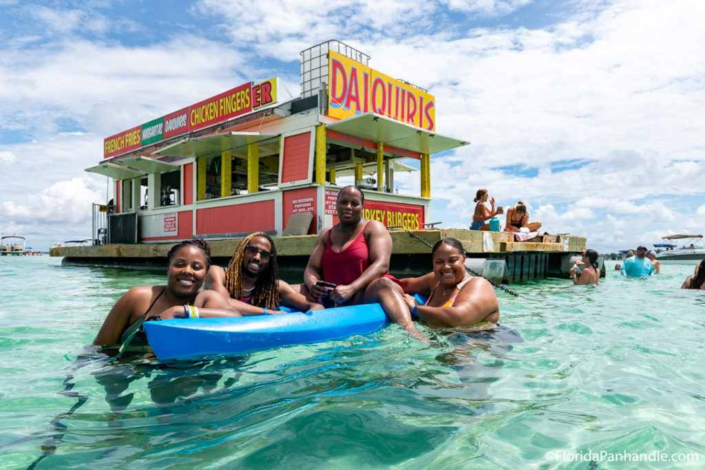 people posing and smiling for the picture in the water at the beach in Crab Island Destin, Florida