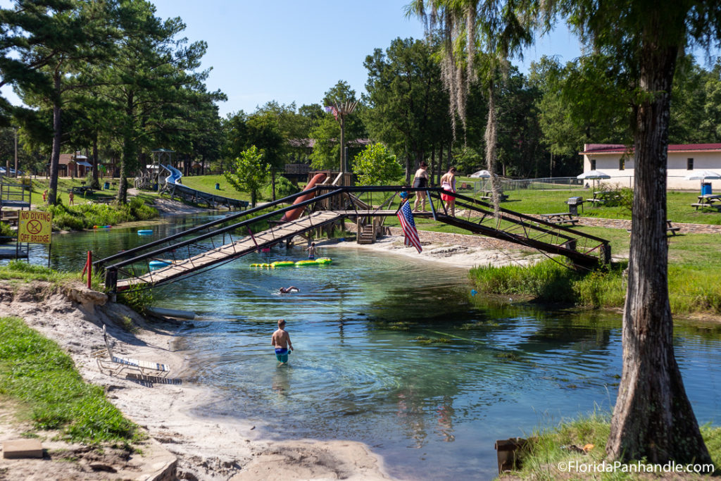 kids walking over bridge with water underneath it