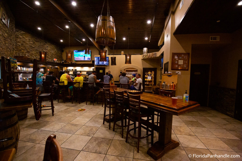 interior of a local brewery spot in pensacola, florida with wooden tables and barrel light