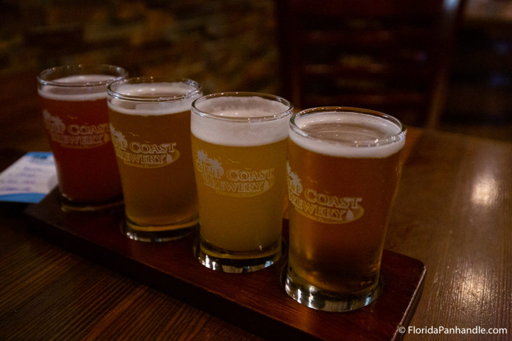 gulf coast brewery flight inside of wooden tray on top of bar top table