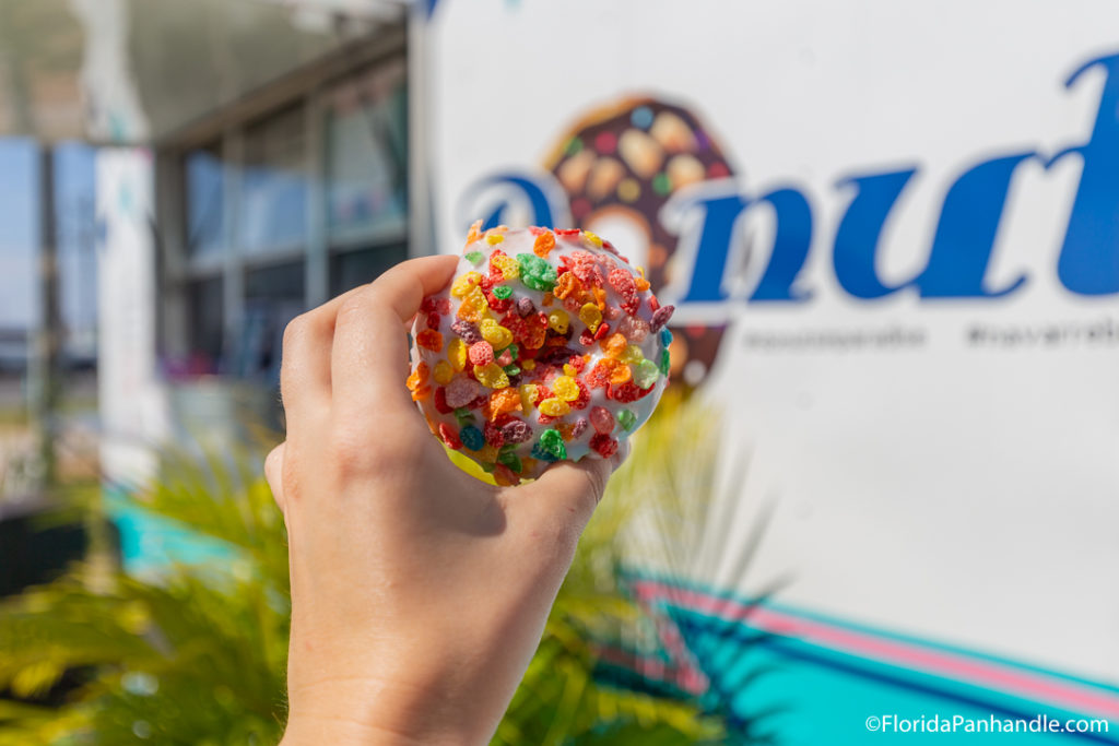 a donut with white icing covered in rainbow colored cereal.