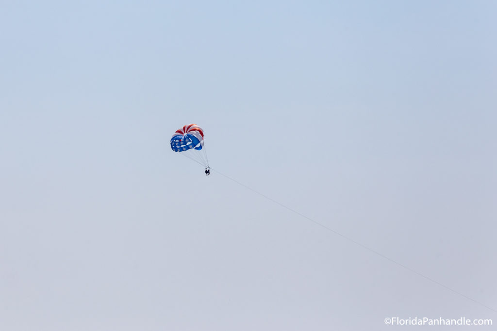 people parasailing high up in the sky with an American Flag parachute 