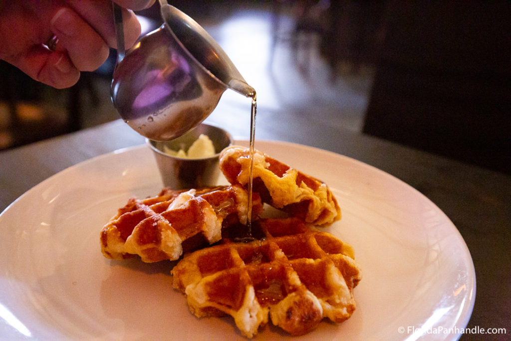 someone pouring maple syrup on top of 3 mini waffles at South Market 