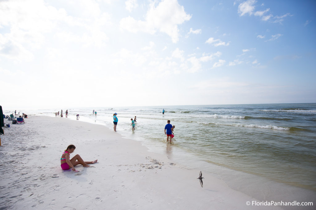 people at the beach standing along the shoreline at Blue Mountain Beach in Florida