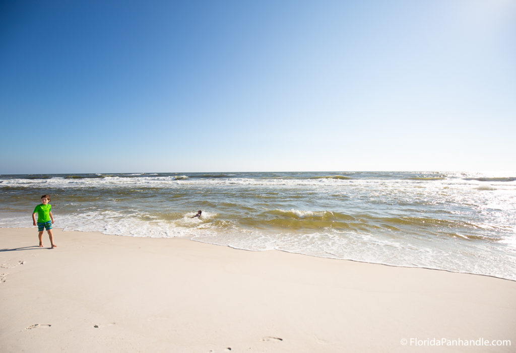 young boy walking along the seashore on a sunny day in 30A