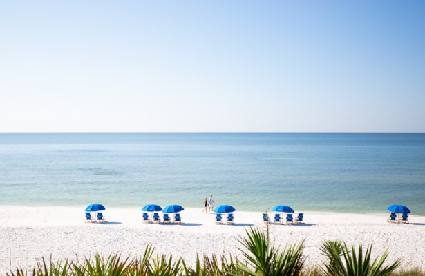 a secluded beach with beach chair and umbrellas set up at Seaside Beach in Florida