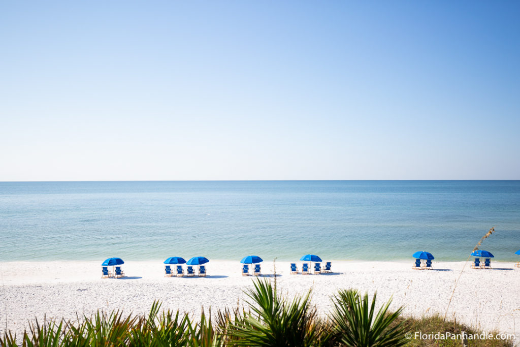 Seaside beach in 30A with blue beach chairs and umbrellas in a row