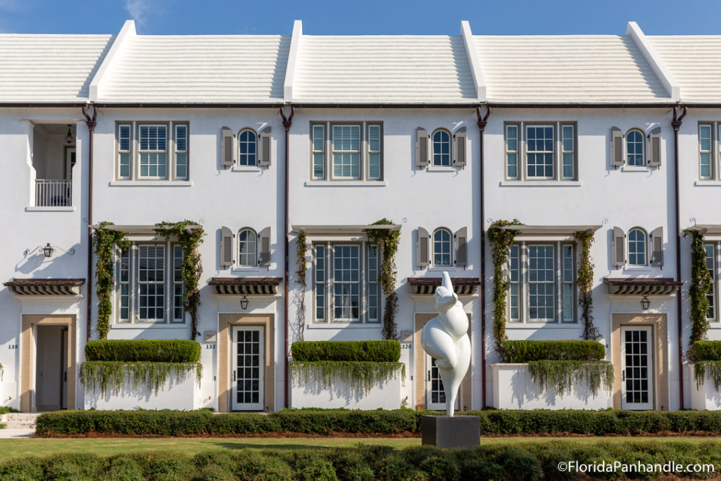 a white french looking building with a statue of a body with no head outside in front