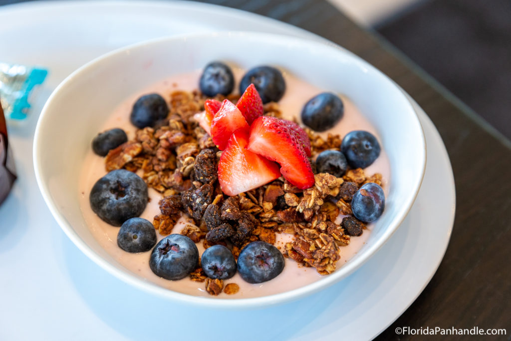 a smoothies bowl with granola, strawberries and blueberries on top