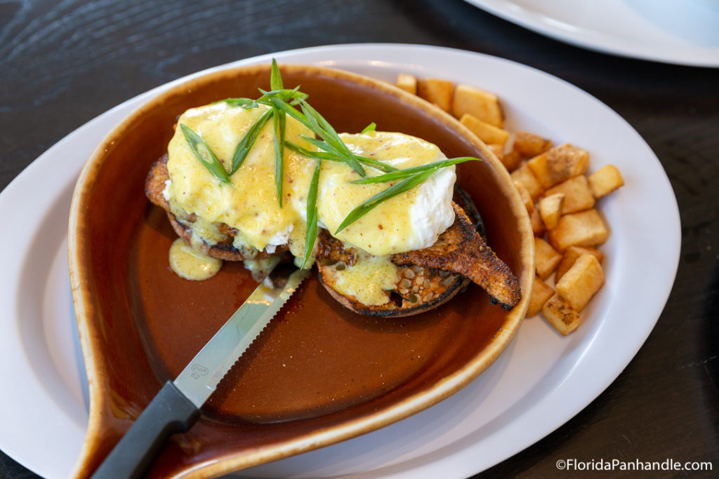 a plate of fried fish with two poached eggs on top with a side of home fries at Crackings