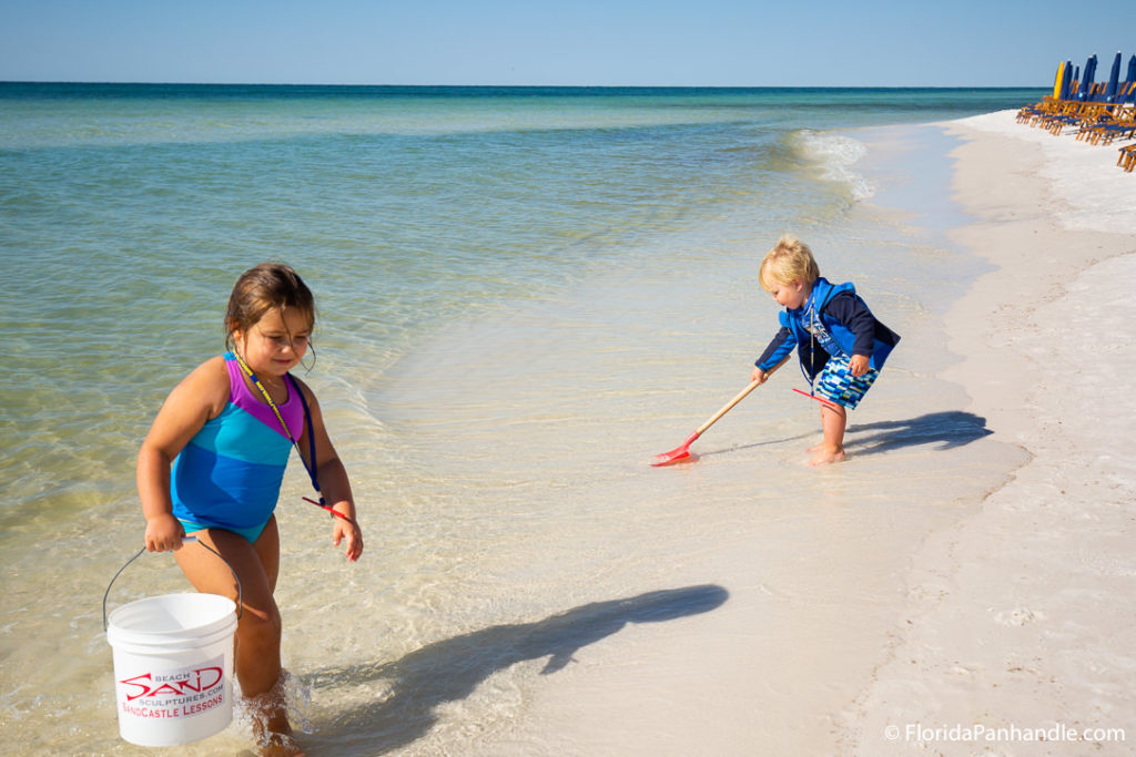 a young boy and girl collecting sand from the beach at the shoreline at Santa Rose Beach in Florida