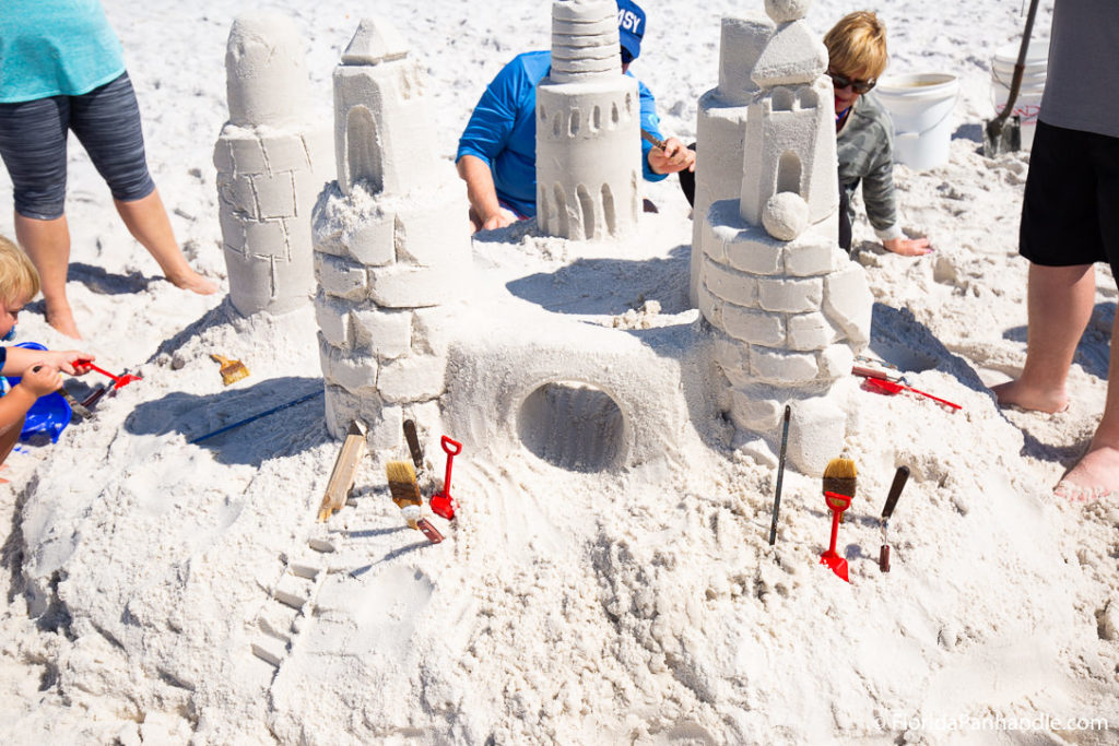 people gathered around building sand castles at the beach