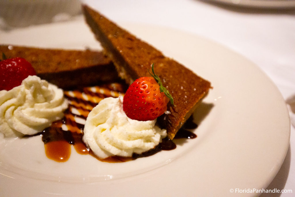 dark brown pie next to whipped cream with strawberry on top of caramel and chocolate drizzle at 30a restaurant