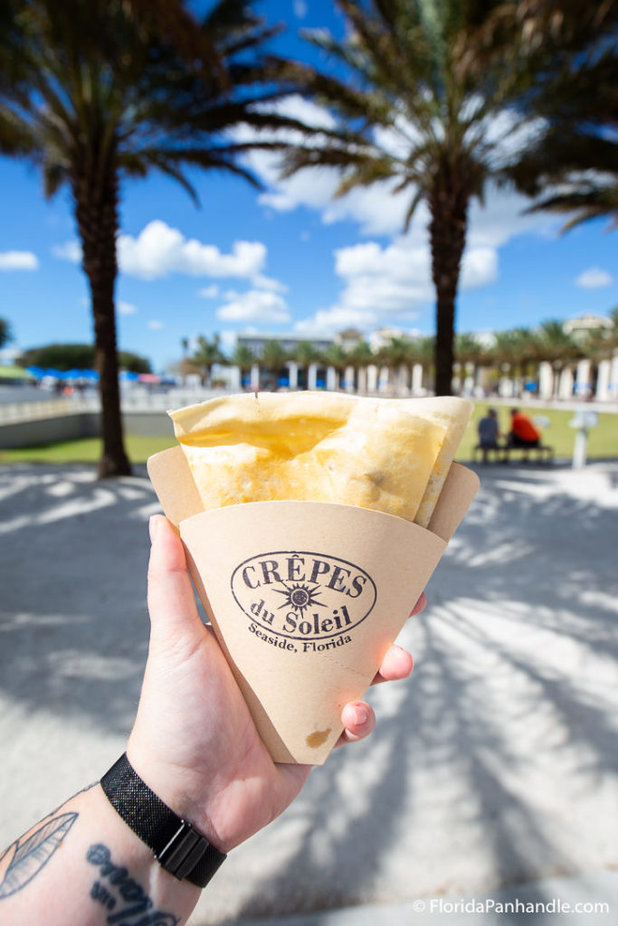 holding a crepe in a cardboard packaging from Crepes de Soleil in 30A