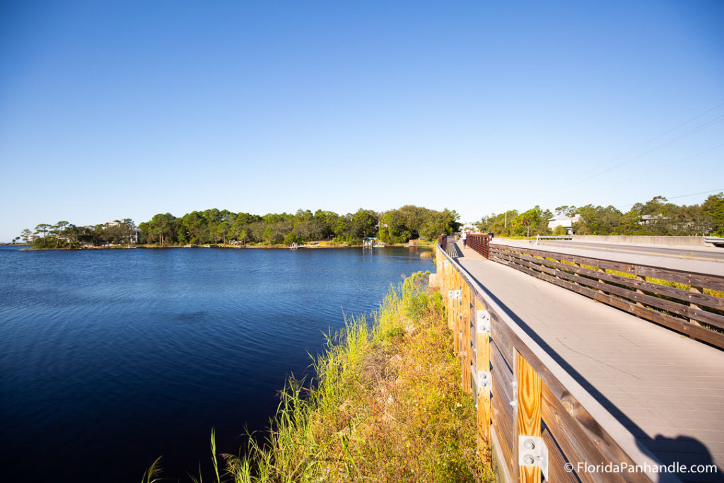 view of a lake from a bridge during the day with bright blue skies