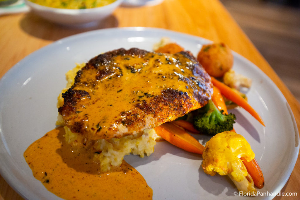 blackened chicken with orange sauce on top next to carrots, broccoli, and cauliflower