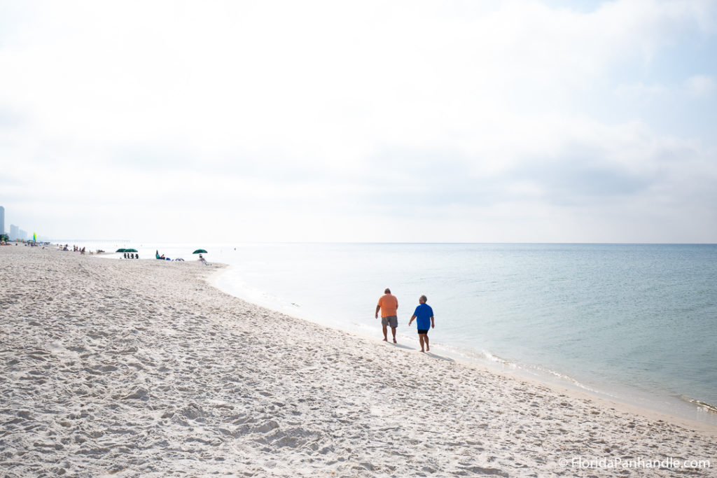 two people walking along the shoreline on a bright sunny day at Laguna Beach in Florida