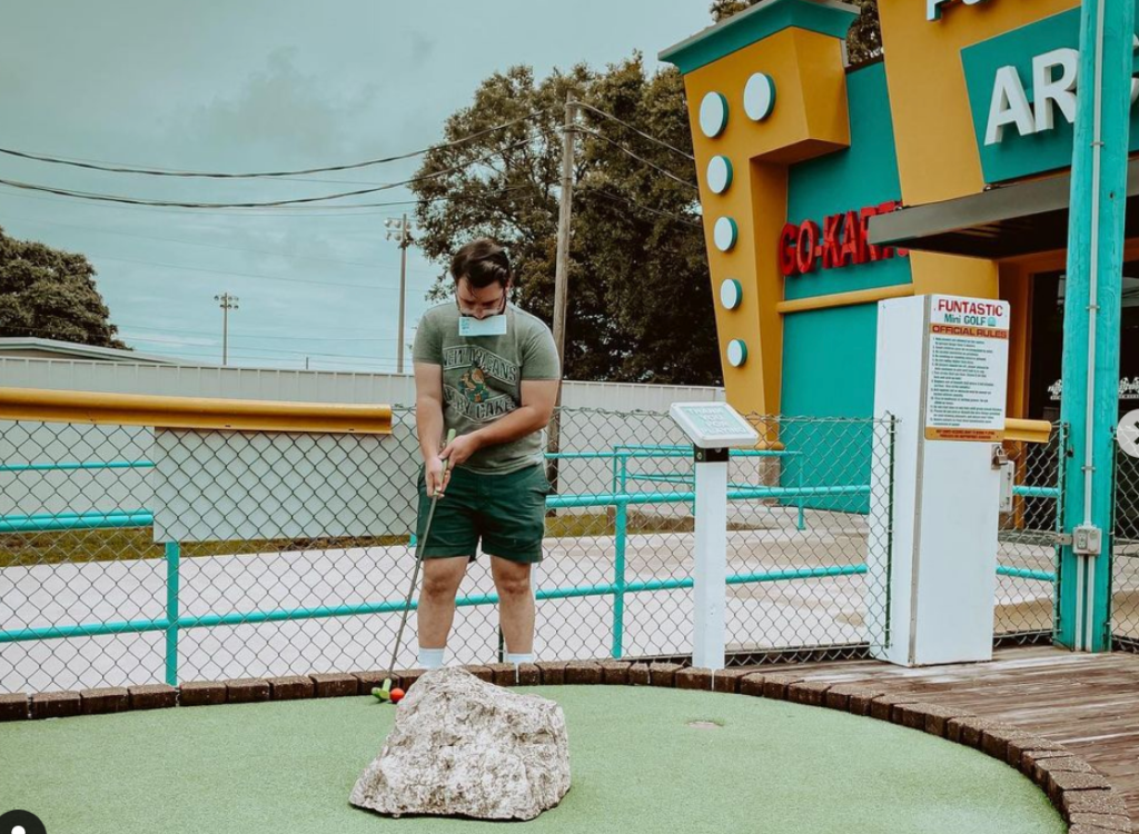 a man playing putt putt wile holding the score card in his mouth at Fast Eddies Fun Center in Pensacola Florida