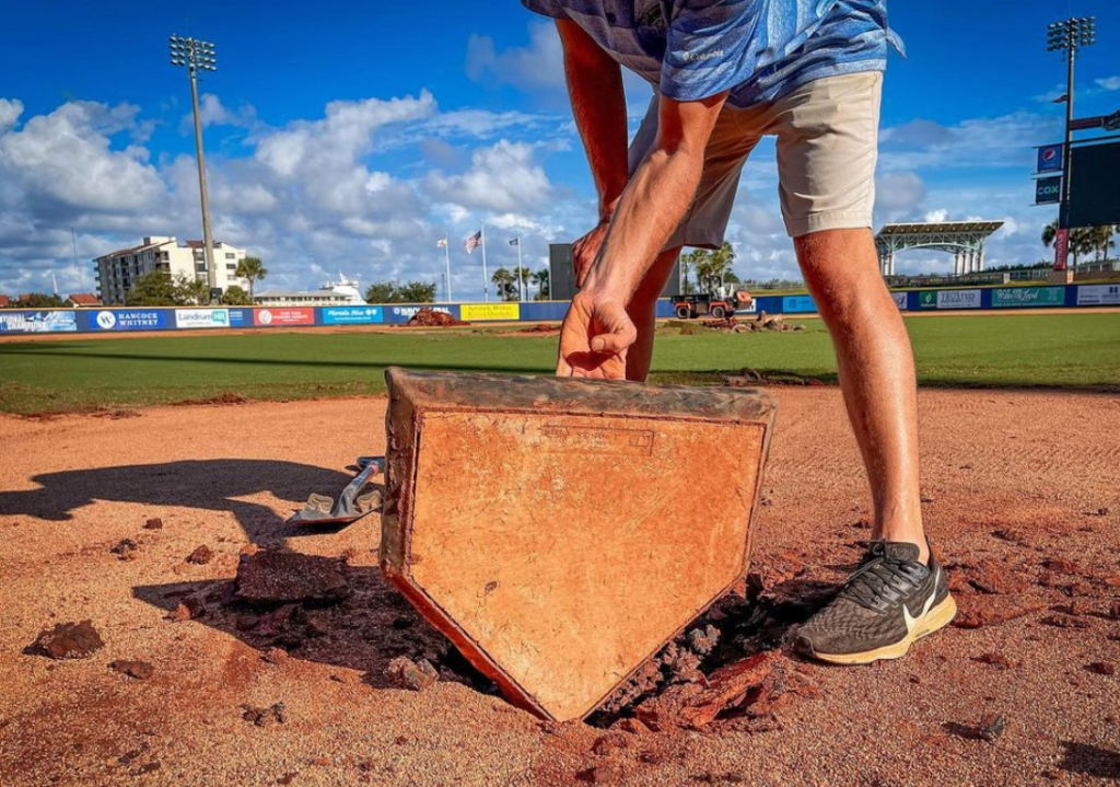 a man lifting the home plate at Pensacola Blue Wahoos Stadium