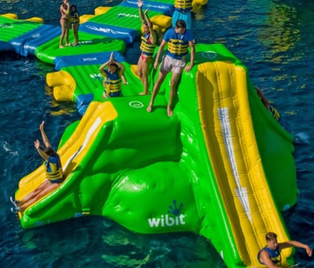 a group of people having fun on a float with a slide out on the water in Pensacola, Florida