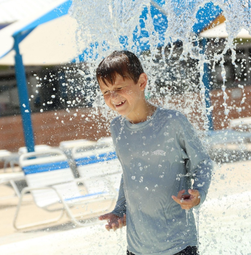 a young boy standing under falling water 