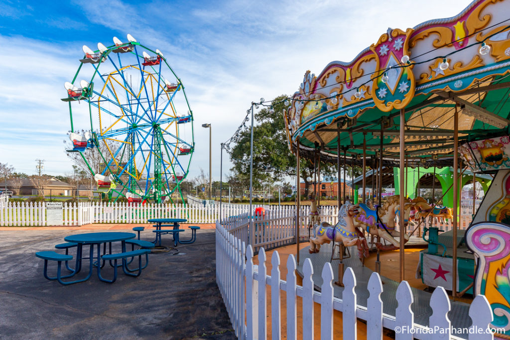 ferris wheel with carousel with lunch tables next to it