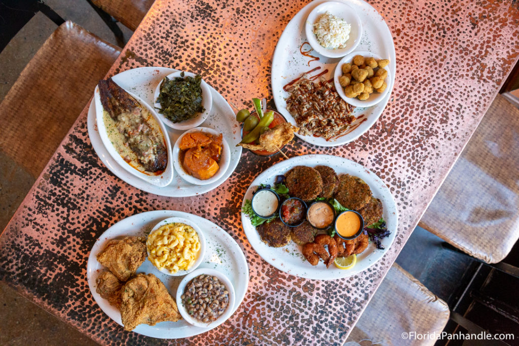 four white plates from five sisters cafe on copper table with food