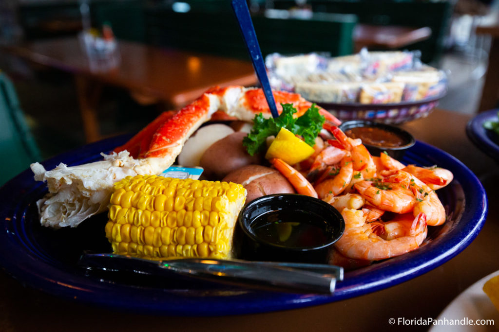 shrimp and seafood with corn and dipping sauces on top of blue plate