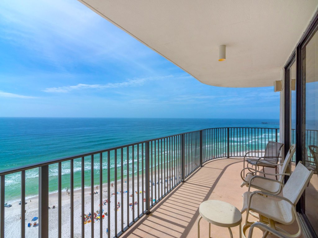 Large balcony with chairs and table with black railing and overlooks of the ocean in panama city beach florida