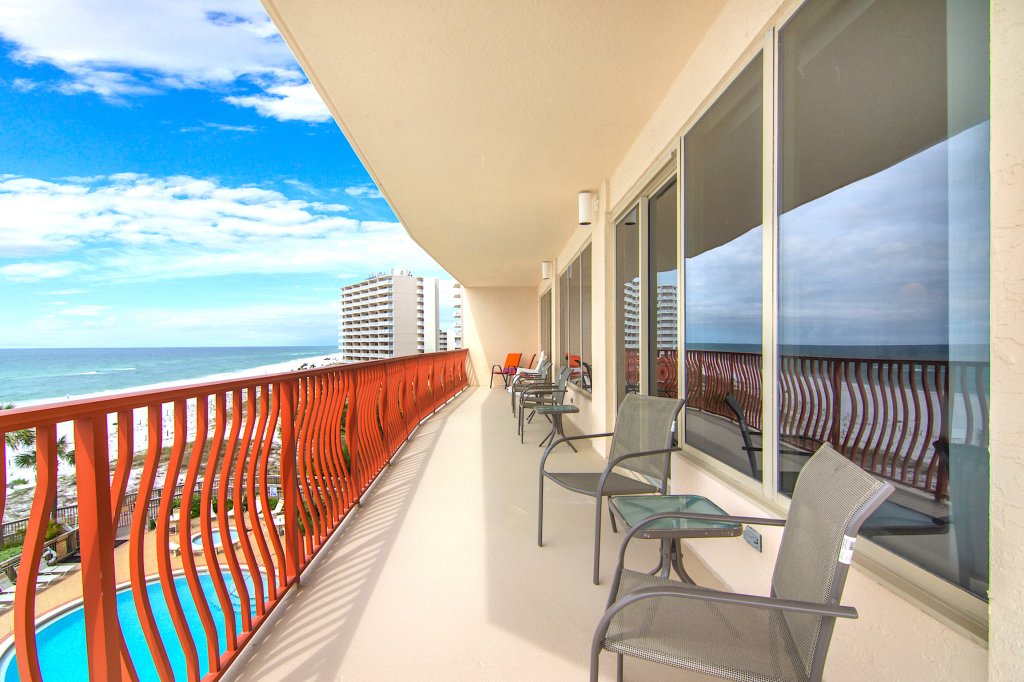 Orange colored balcony with several chairs on the balcony as well as patio tables with views of the ocean