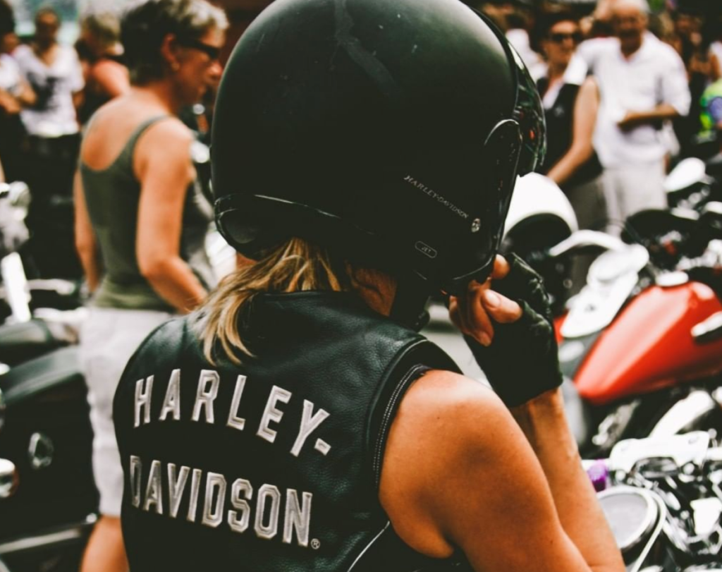 the back of a woman wearing helmet wearing Harley Davidson leather shoulder-less jacket 