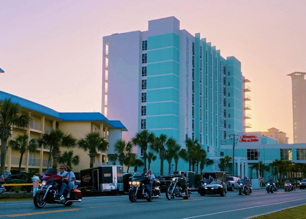 motorcyclist riding down the street during the sunset with pink purple skies in panama city beach