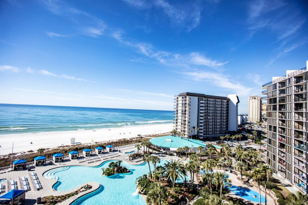 balcony view of beach front resort and pool with palms trees in Panama City Beach