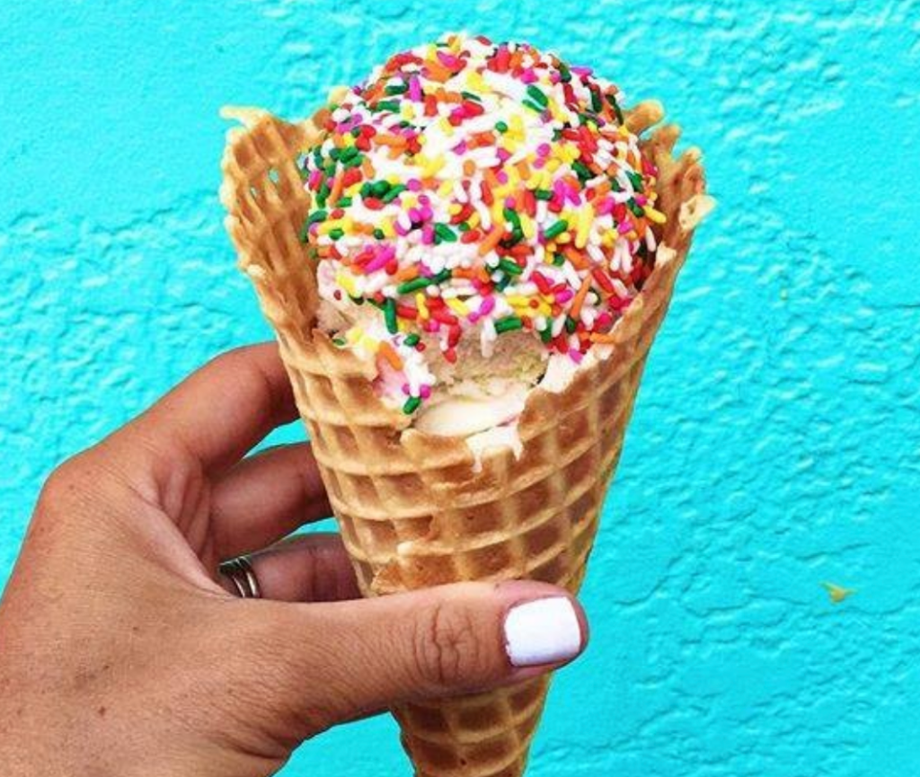 ice cream in a cone, rainbow sprinkled all over, dessert