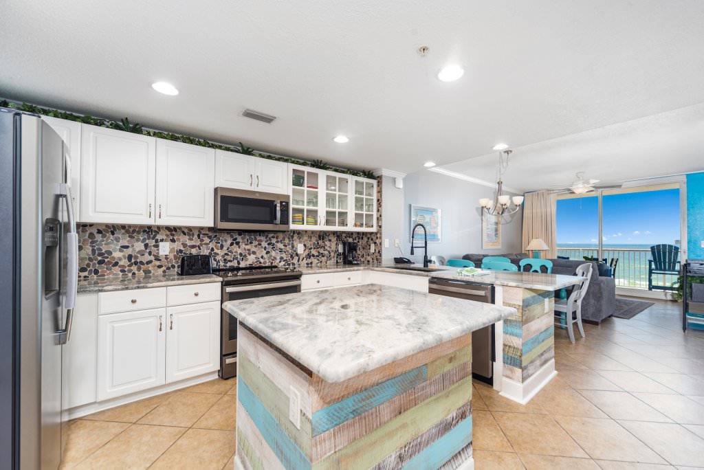 a kitchen with a squared island in the middle and a living area behind it with views to the ocean at Majestic Beach Resort in Panama City Beach Florida