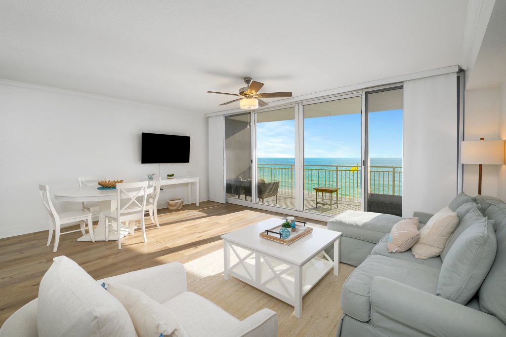 a nice clean beachy living area with sliding glass doors to the balcony with and ocean view at Emerald Beach Resort in Panama City Florida