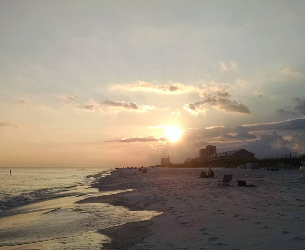 sun peeking out from being the clouds, sunset, at the beach, ocean, waves