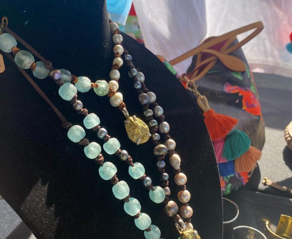 vendor at grand lagoon waterfront farmers market necklace next to bag