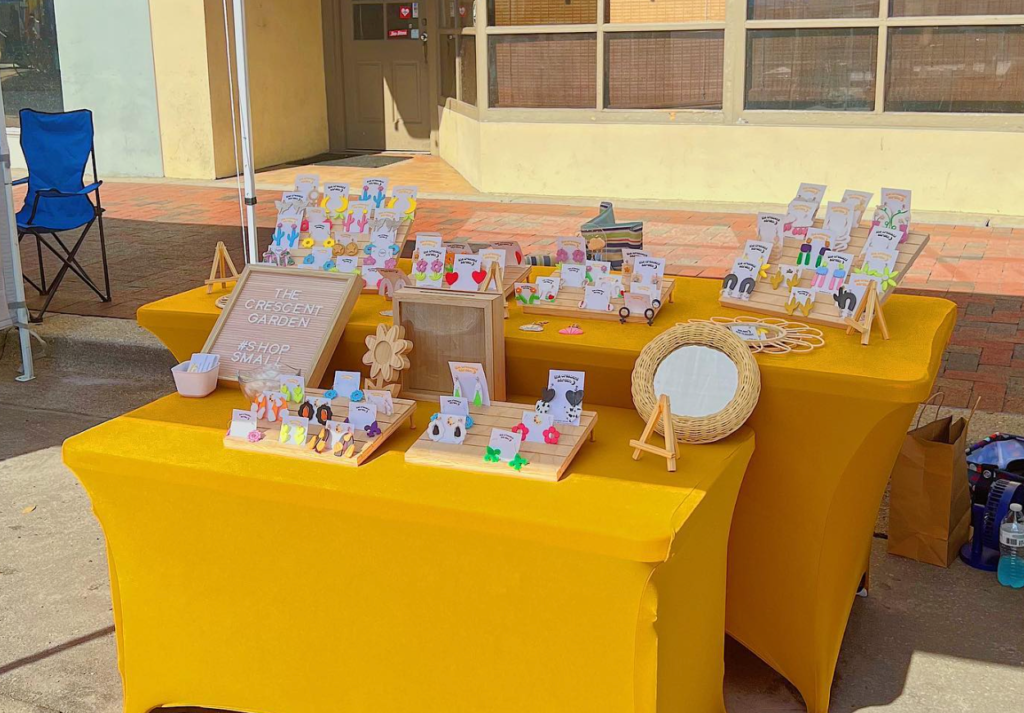 gallery night in pensacola florida, table with yellow cover and handmade jewelry on top