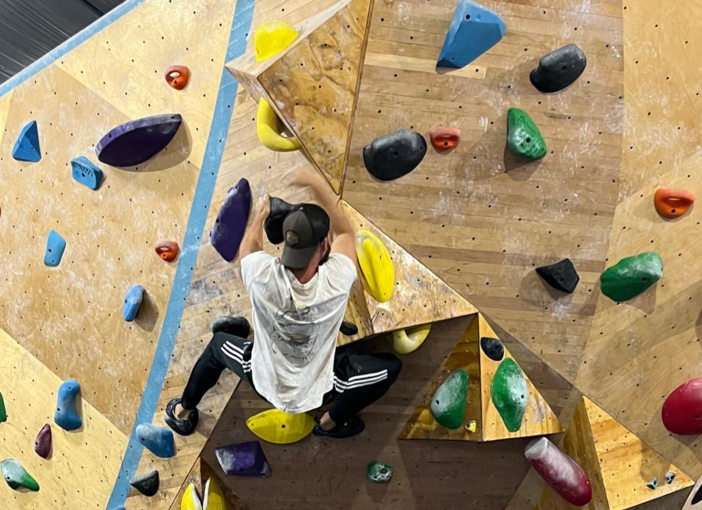 man climbing on top of rock wall in destin fl